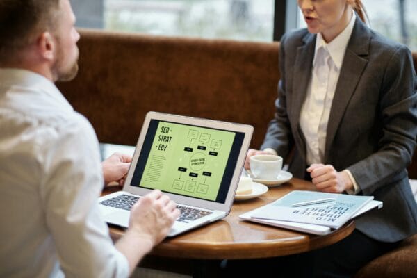 advanced seo strategies - A man and woman engaged in a business meeting discussing SEO strategy in a cozy cafe setting.