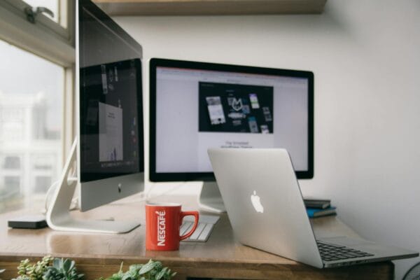 website performance optimization - A bright modern office setup with computers and a mug on a desk.