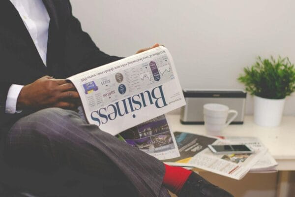 seo news today - Businessman reading a financial newspaper at a desk, highlighting finance and commerce theme.