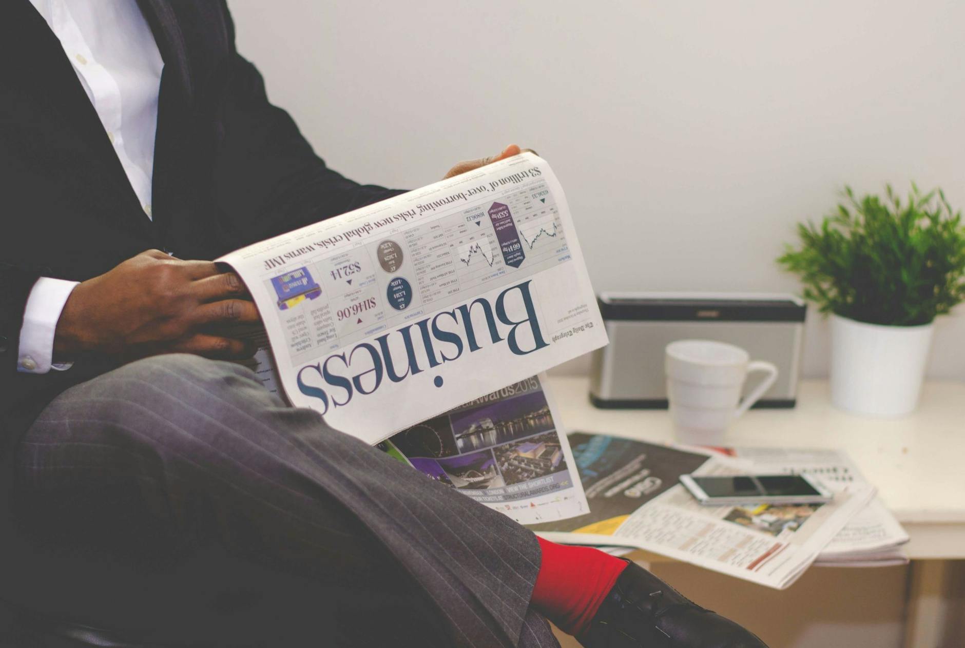 seo news today - Businessman reading a financial newspaper at a desk, highlighting finance and commerce theme.