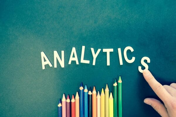 local seo strategies - Colored pencils and letters spelling 'ANALYTICS' on a textured background with a hand.
