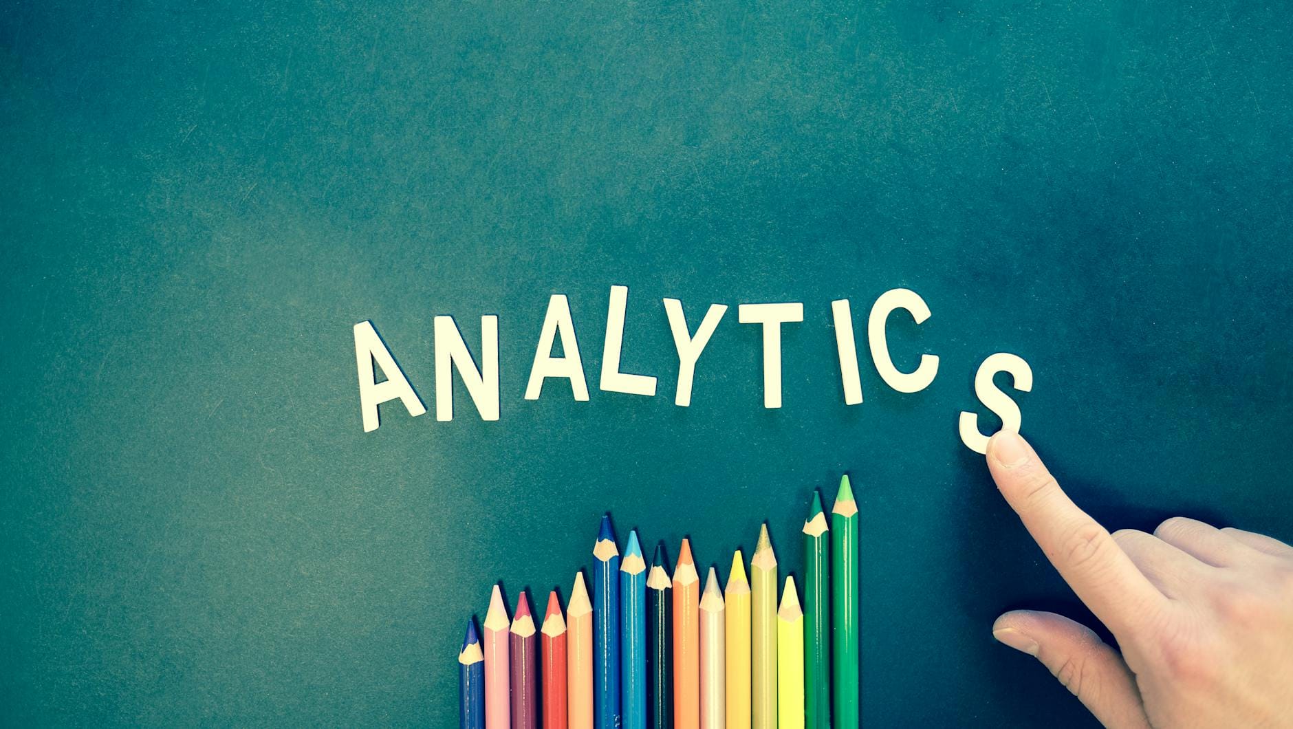 local seo strategies - Colored pencils and letters spelling 'ANALYTICS' on a textured background with a hand.