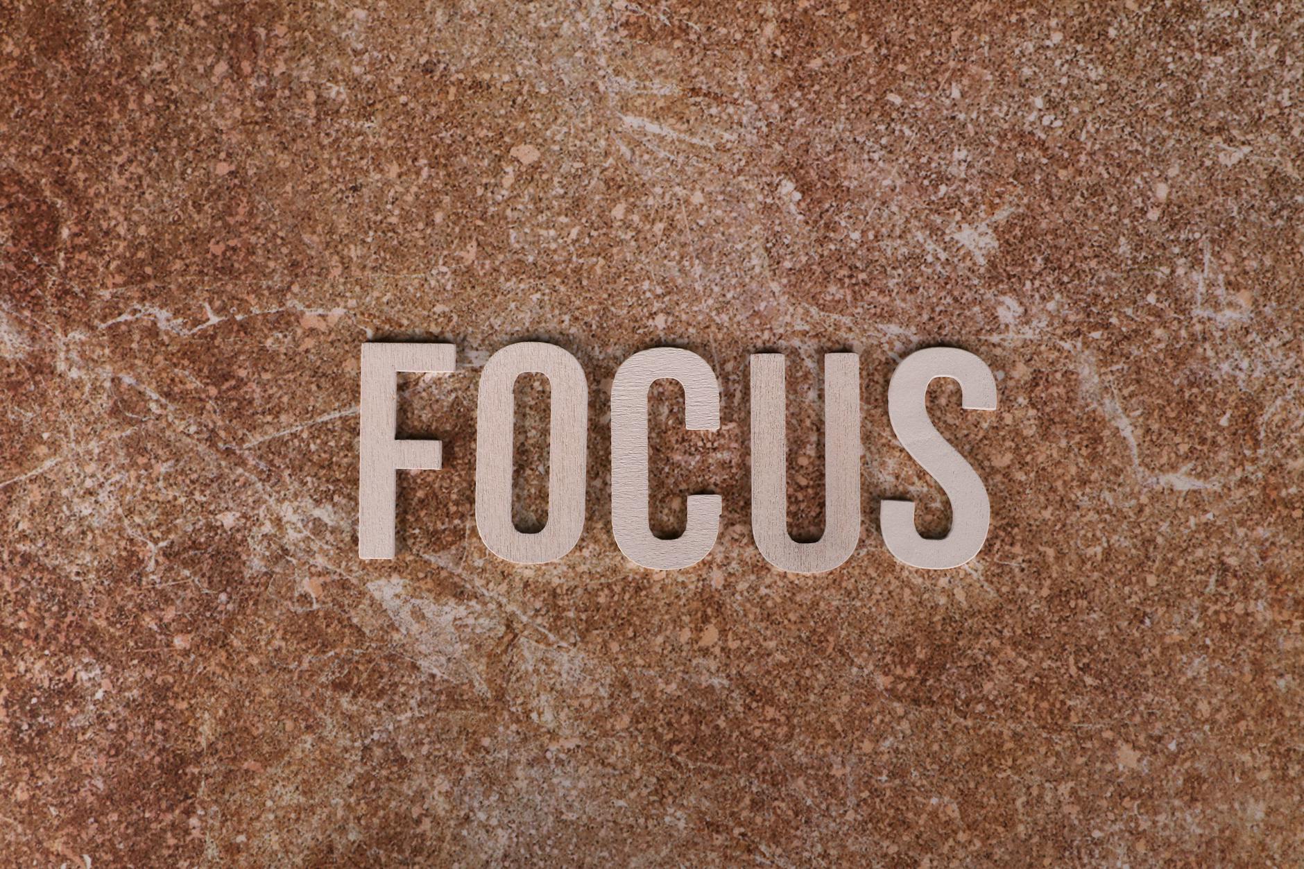 cara mencari long tail keyword - Wooden letters spelling 'FOCUS' on a textured brown surface for emphasis.