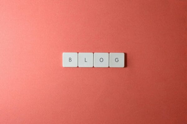 AI untuk konten blog - A minimalist image of keyboard keys spelling 'BLOG' on a coral background.