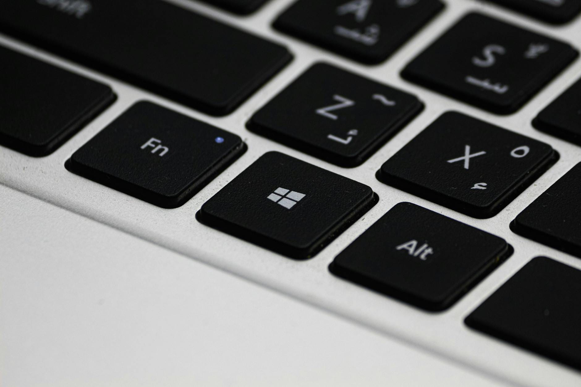 fungsi alt text gambar - Detailed view of a laptop keyboard featuring Arabic letters and Windows key.