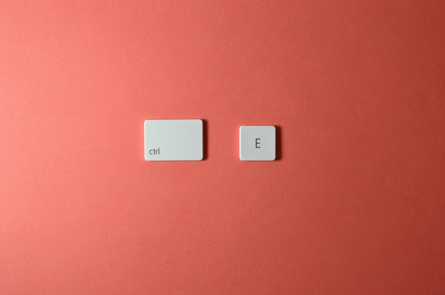 E-E-A-T SEO - A minimalist arrangement of 'Ctrl' and 'E' keyboard keys on a coral background.