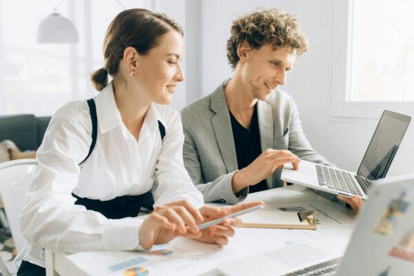 engagement website - Two colleagues collaborating on a project, using laptops and documents in a modern office setting.