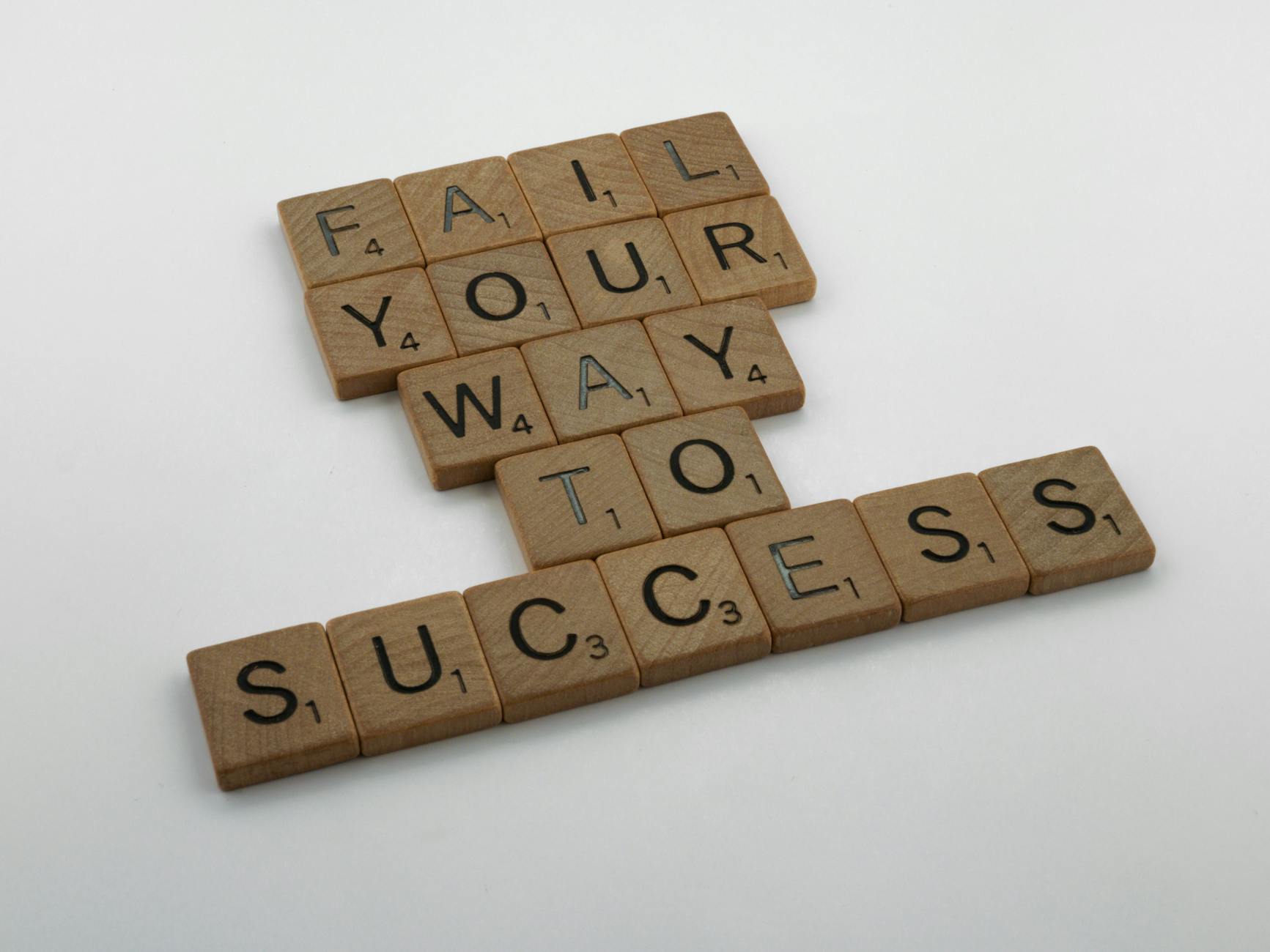 cara mengatasi keyword cannibalization - Wooden tiles spell 'Fail Your Way to Success' emphasizing perseverance.