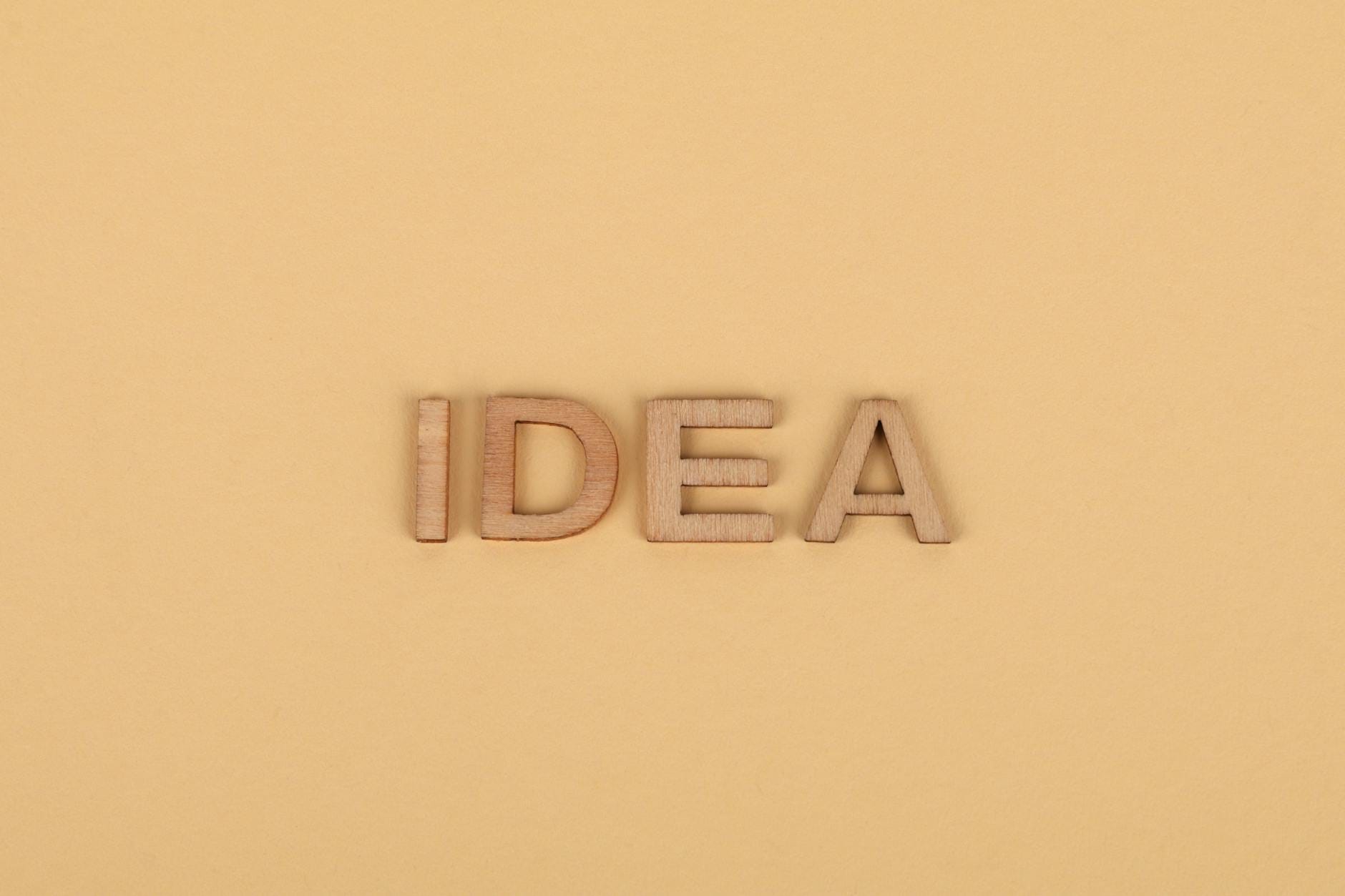 membaca keyword difficulty - Wooden letters forming 'IDEA' on a plain beige surface, representing creativity.