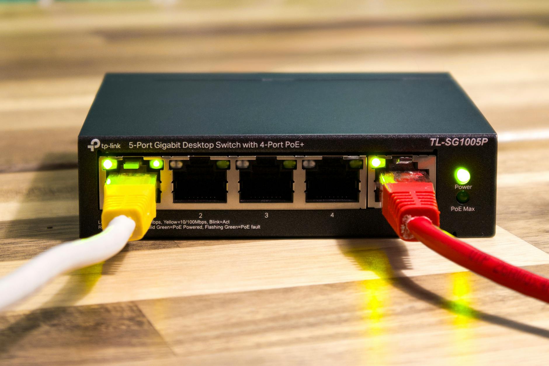 fungsi nofollow link - Close-up of a TP-Link Ethernet switch with yellow, red, and white cables connected.