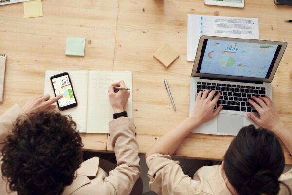 SEO Programmatic - Overhead shot of two colleagues collaborating with devices and notes in a business meeting.