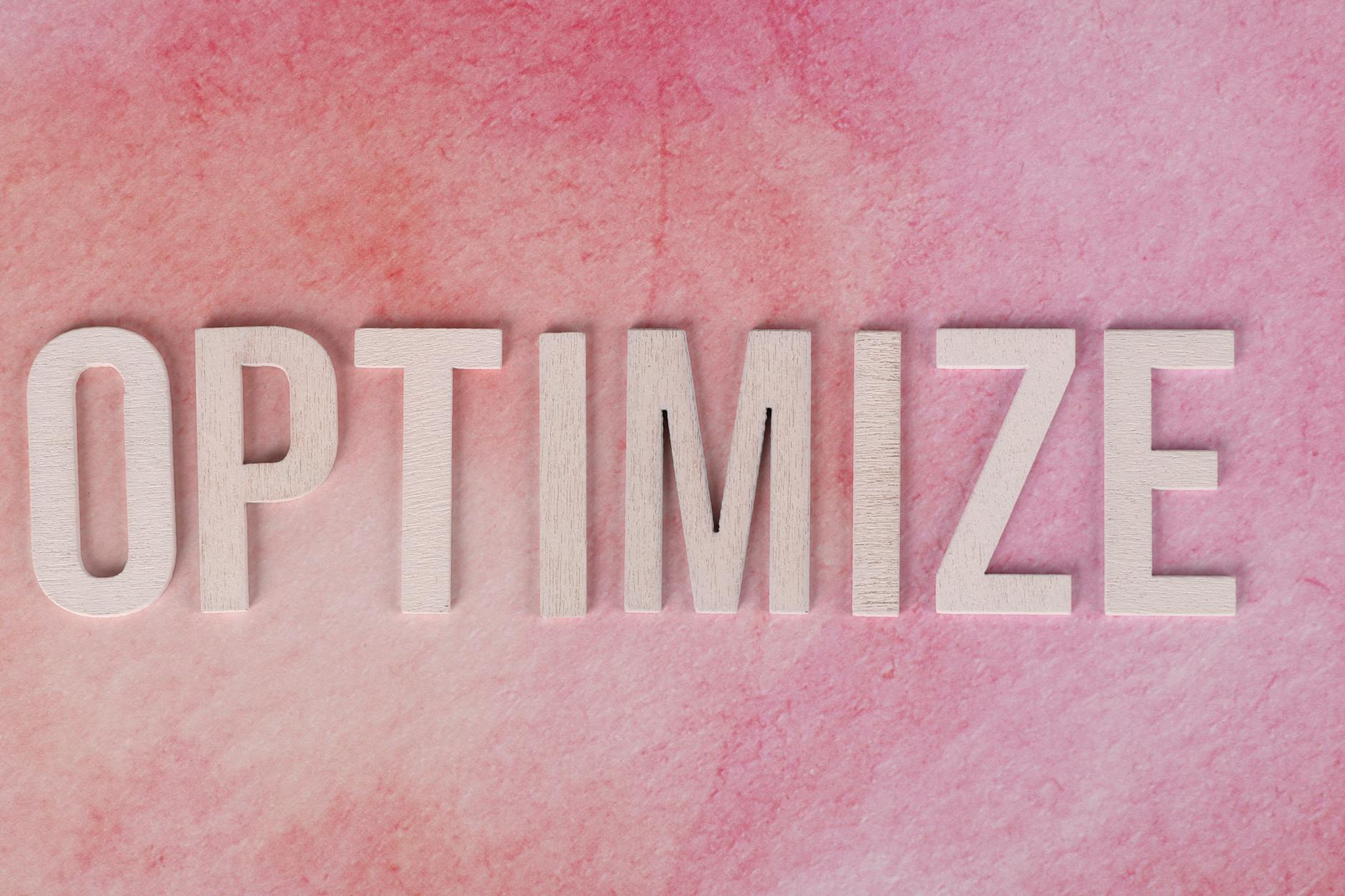 SEO semantik - Creative display of the word 'OPTIMIZE' on a pink textured surface.