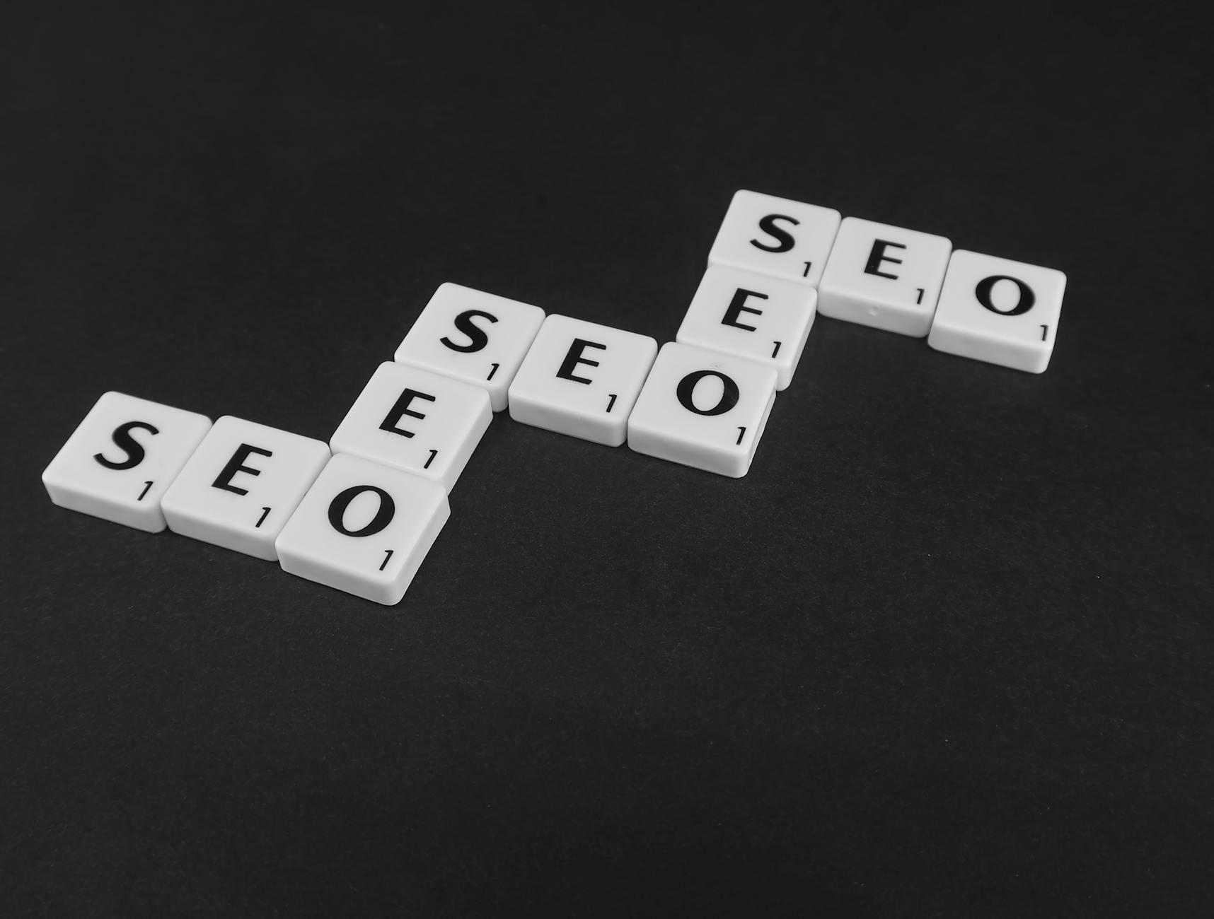 apa itu seo dan bagaimana cara kerjanya - SEO spelled with Scrabble tiles on a black surface, representing search engine optimization concepts.