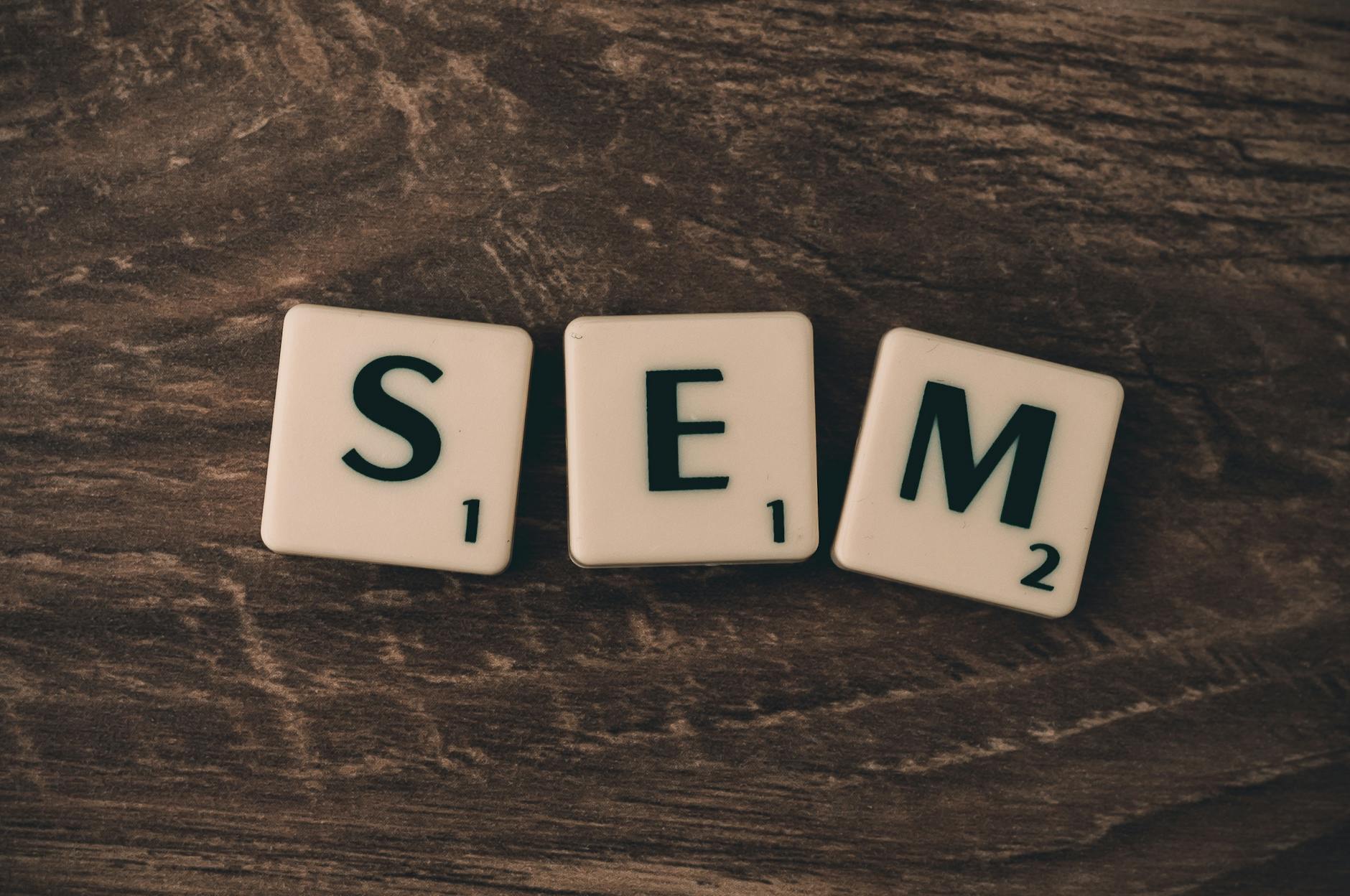 SEO untuk pemula - Wooden background with letter tiles spelling SEM, representing search engine marketing.