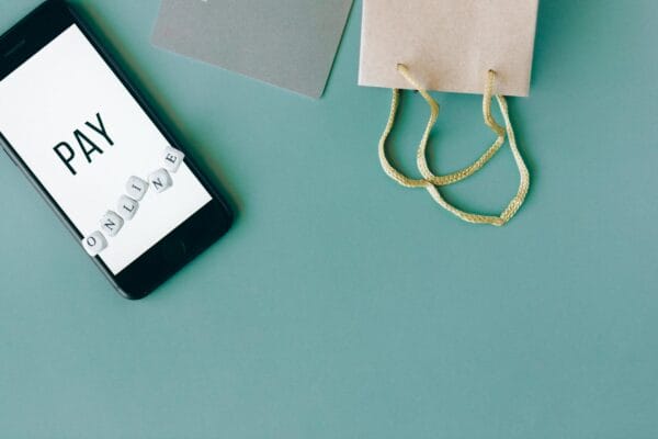 cara meningkatkan traffic website toko online - Illustration of online payment with smartphone, credit card, and shopping bag on mint background.