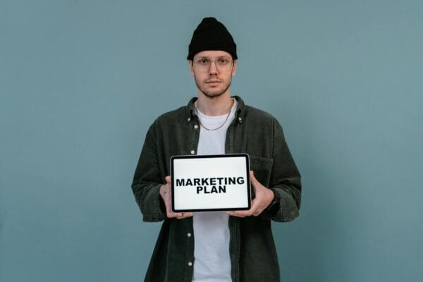 digital marketing vs traditional marketing - Caucasian man wearing beanie holds a digital marketing plan on a tablet.