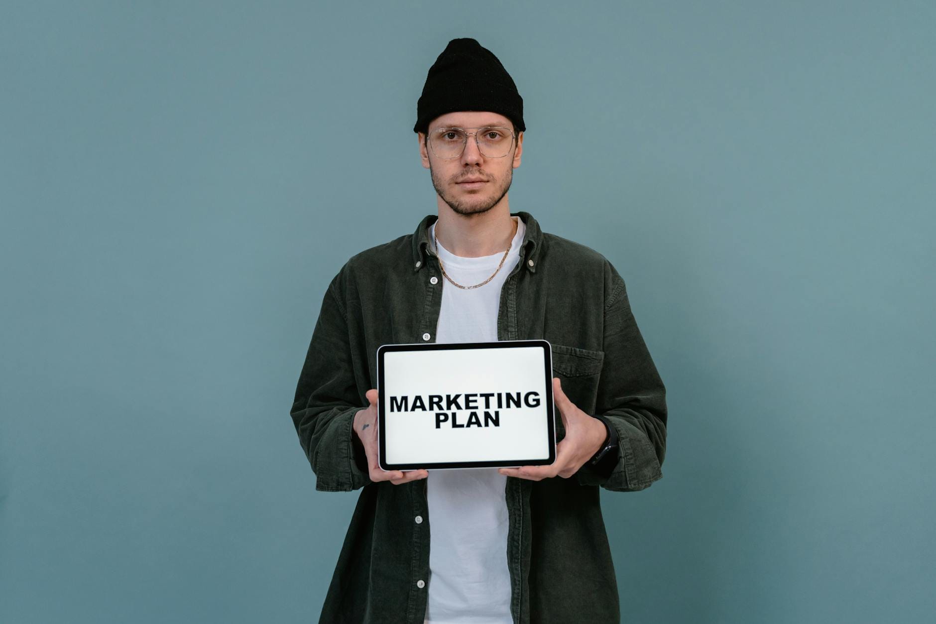digital marketing vs traditional marketing - Caucasian man wearing beanie holds a digital marketing plan on a tablet.