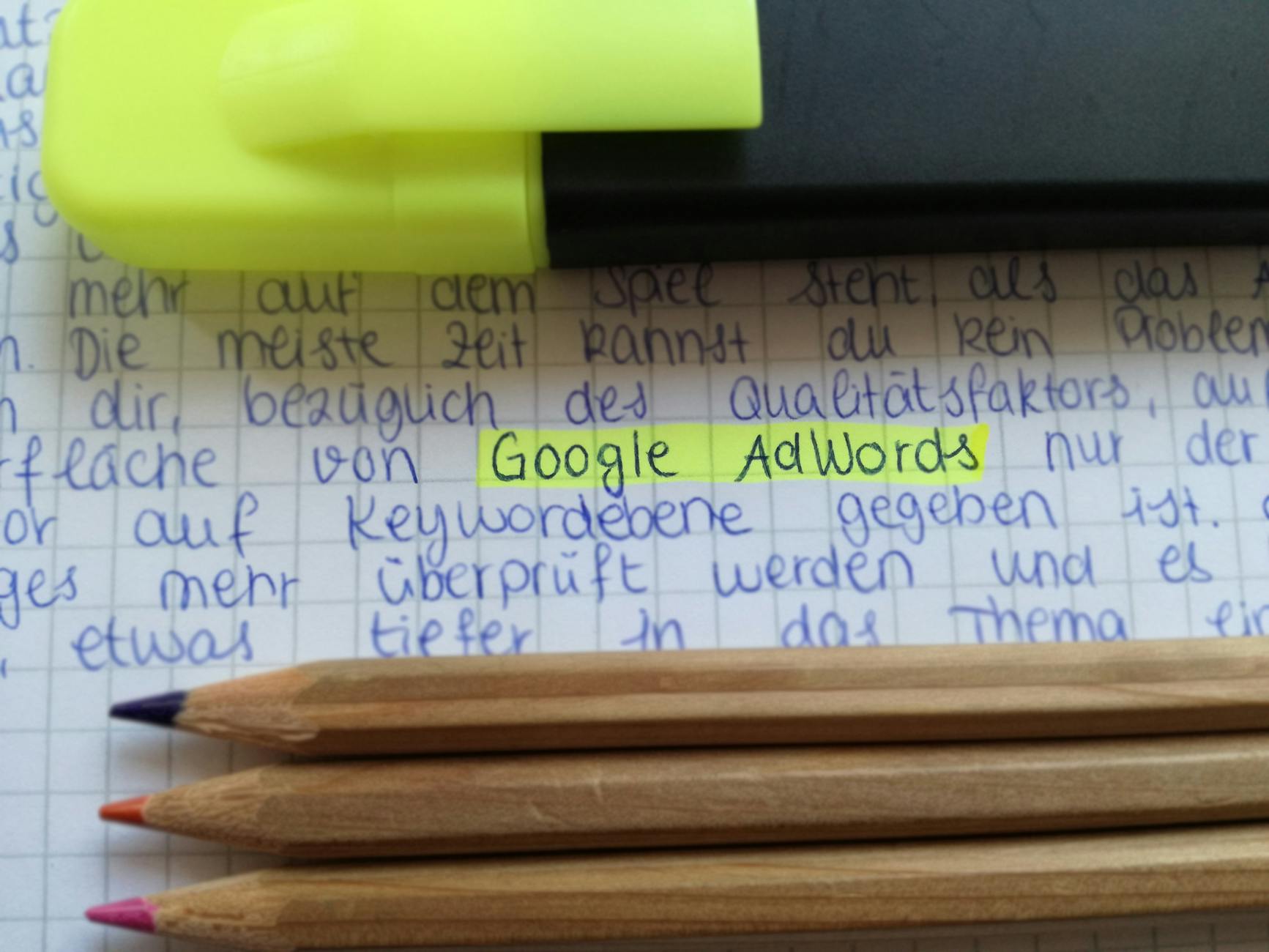 google keyword rank checker - Close-up of colorful pencils on handwritten notes with Google AdWords highlighted.