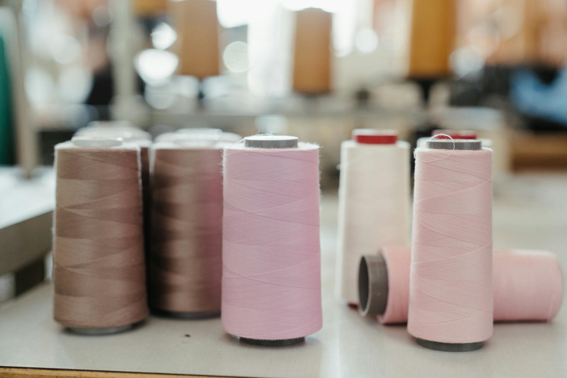 main thread blocking time - Close-up view of various colored thread spools in a sewing workshop setting.