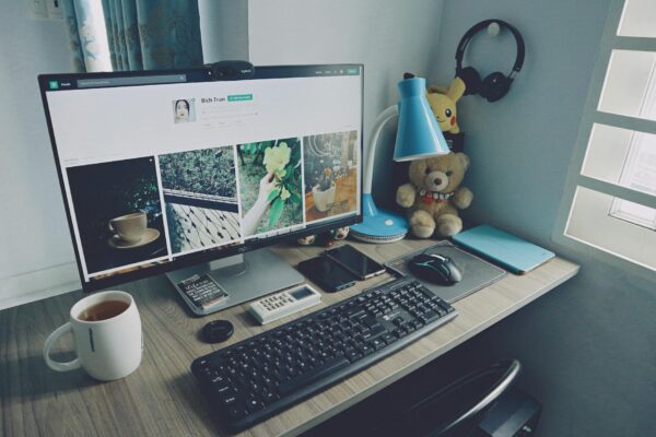 membuat website dengan wordpress - A tidy home office desk setup with a computer, keyboard, and personal items, creating a cozy work atmosphere.