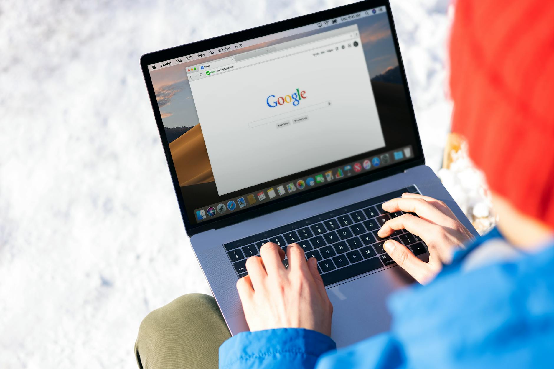 seo basics for beginners complete guide - Individual typing on a laptop outdoors with snow, accessing the internet.