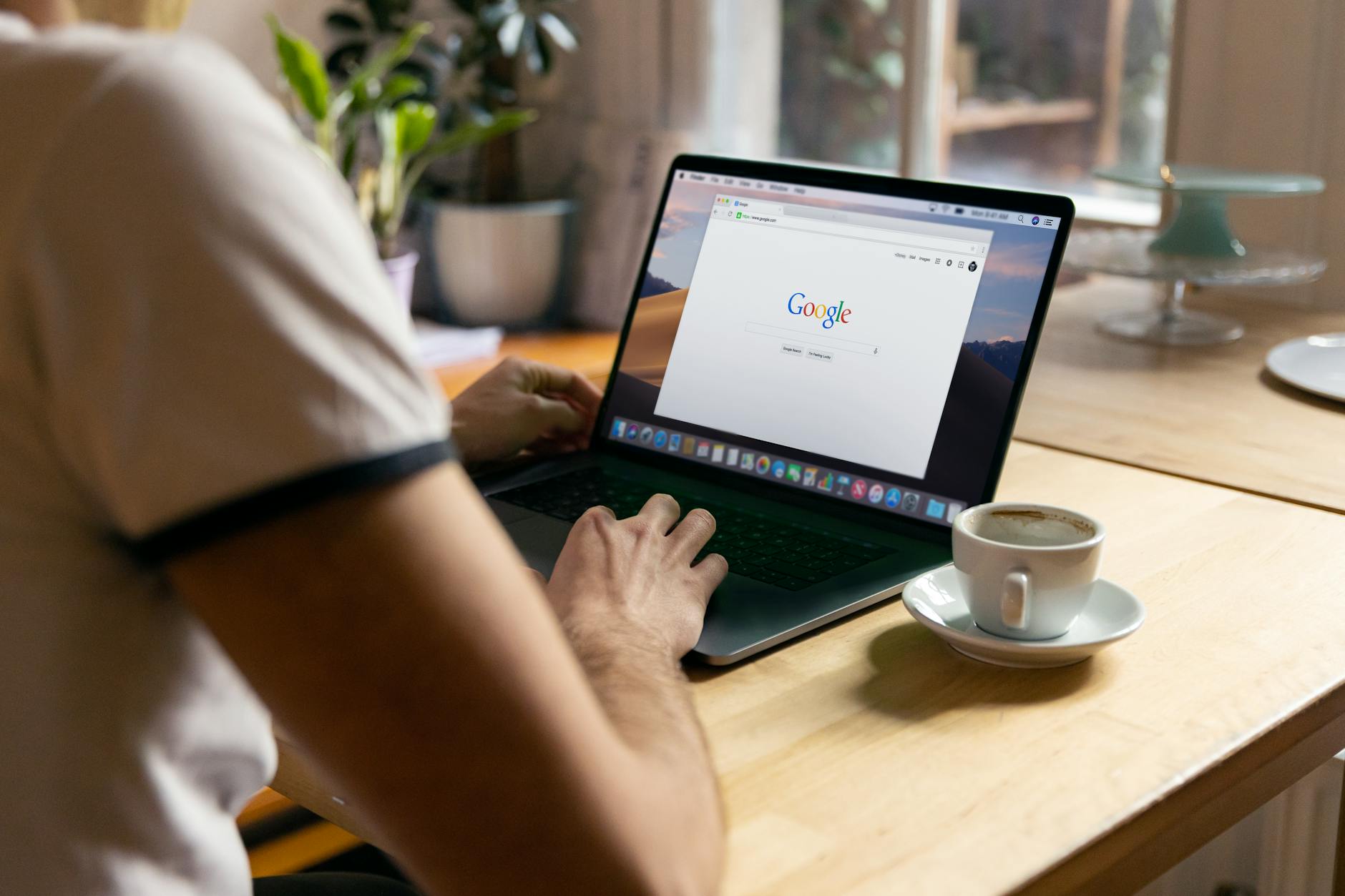 seo basics for beginners complete guide - A person working on a laptop in a cozy indoor setting with a coffee cup on the table.