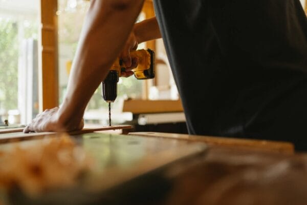 how to improve readability - Crop anonymous male carpenter making hole on wooden plank with drill during work in studio on sunny day