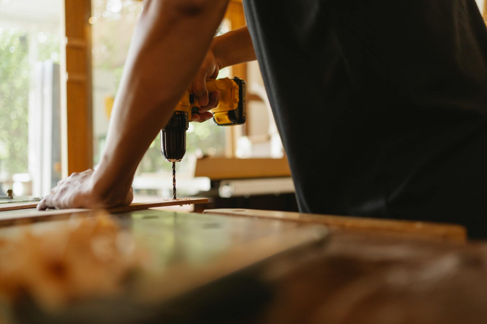 how to improve readability - Crop anonymous male carpenter making hole on wooden plank with drill during work in studio on sunny day