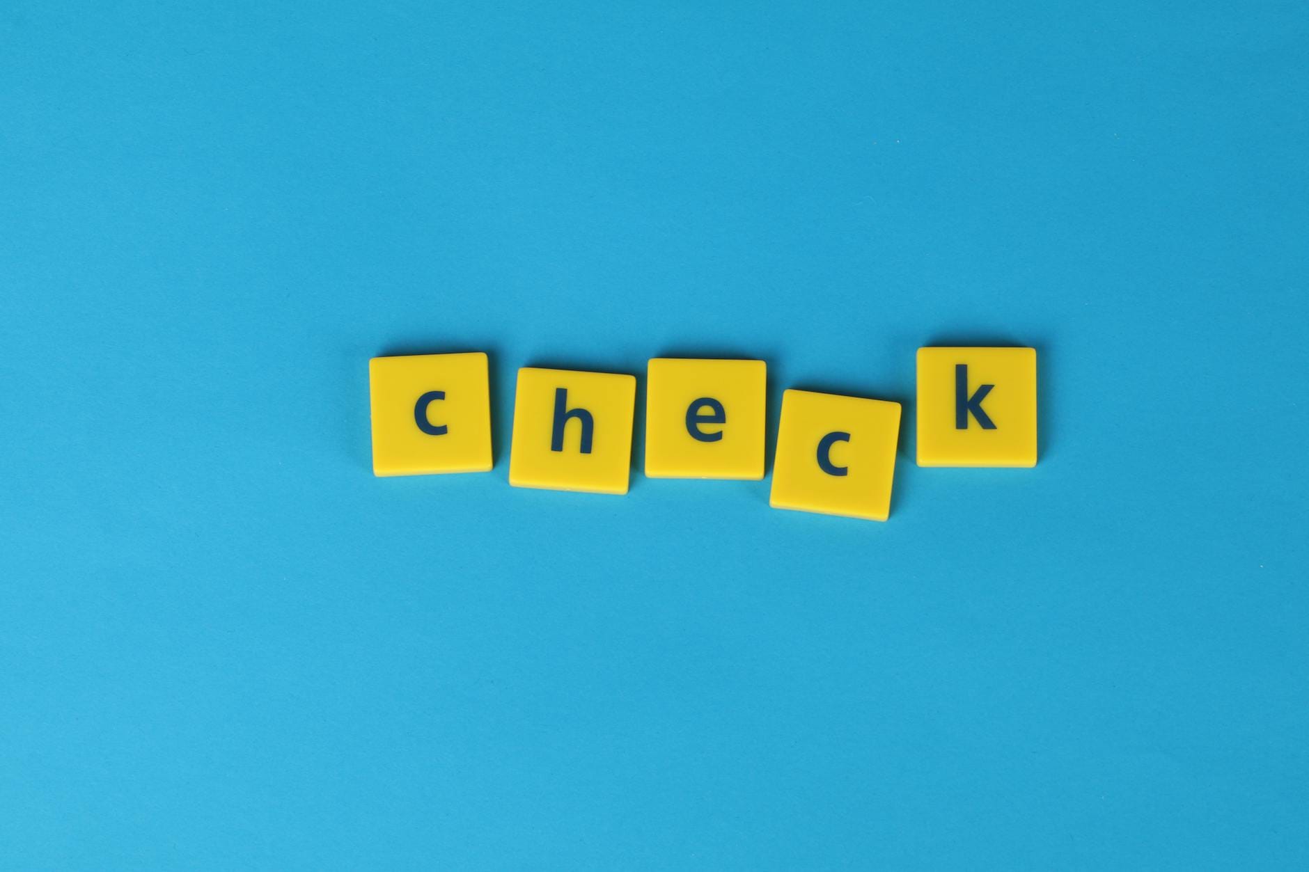 free keyword rank checker - Yellow letter tiles spelling 'check' on a vibrant blue background, conveying approval or verification.