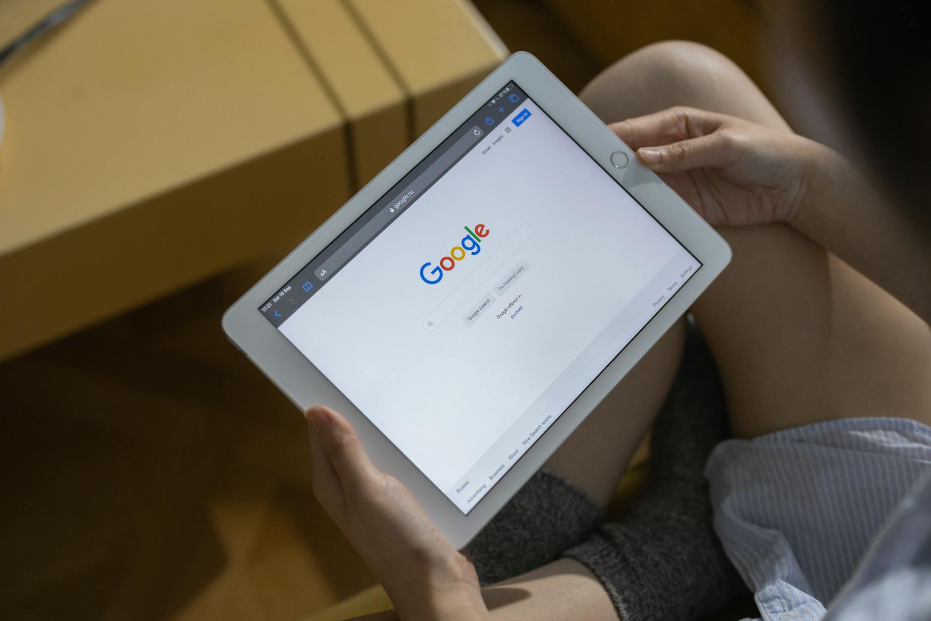 google serp checker - Close-up of hands holding a tablet showing the Google search page.